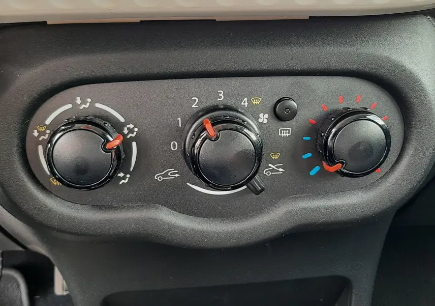 Vue rapprochée du tableau de commande noir avec bouton de régulateur de vitesse et porte-gobelets dans une Renault Twingo III blanc cristal.