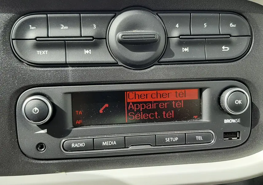 Gros plan sur la console centrale noire et blanche du Renault Twingo III blanc cristal, avec écran radio affichant "FUN".