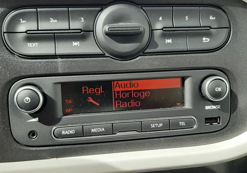 Détail de la console centrale de la Renault Twingo III blanche, affichant l’écran radio avec options de téléphone et commandes intégrées.