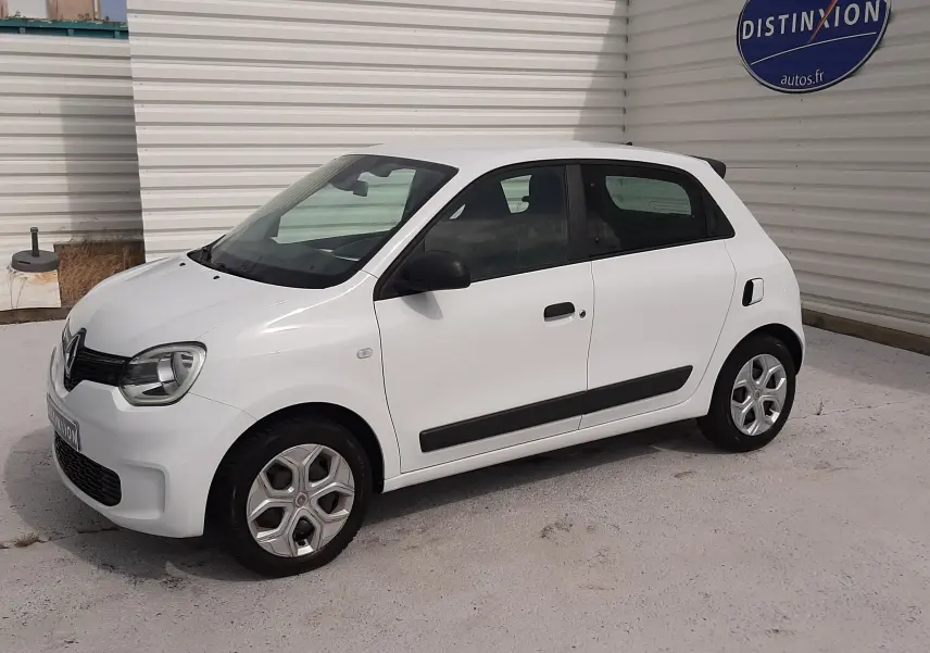 Vue de face d'une Renault Twingo III blanc cristal avec calandre noire et phares allumés sur fond clair.