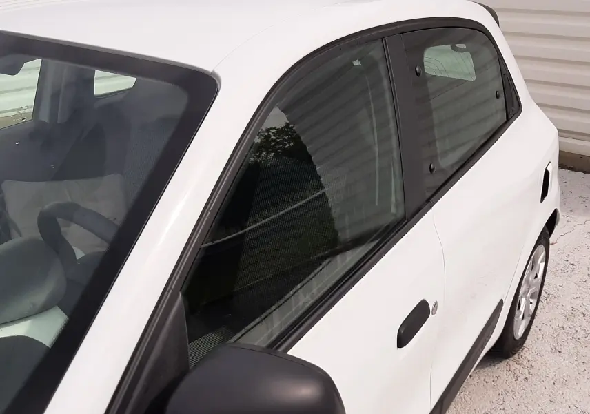 Renault Twingo III blanc cristal vue 3/4 avant droit, compacte cinq portes avec protections latérales noires.