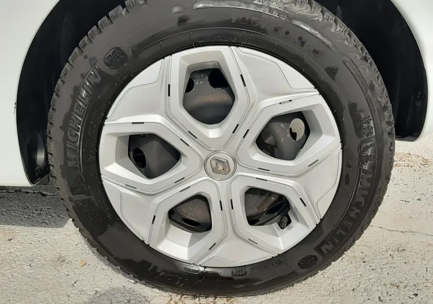 Gros plan sur le phare avant gauche allumé de la Renault Twingo III blanc cristal, avec calandre noire et carrosserie lisse.
