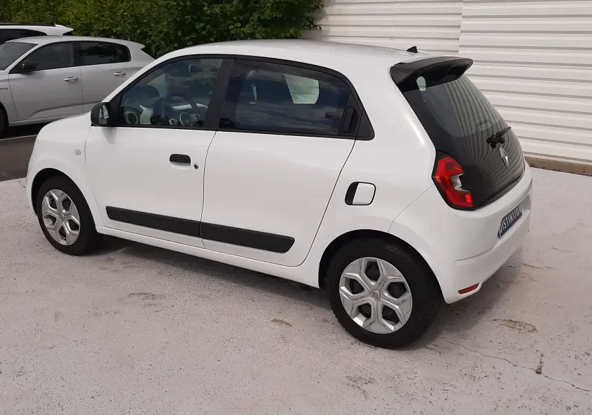 Gros plan sur la roue avant droite d'une Renault Twingo III blanche, mettant en valeur le pneu Michelin tout-terrain.