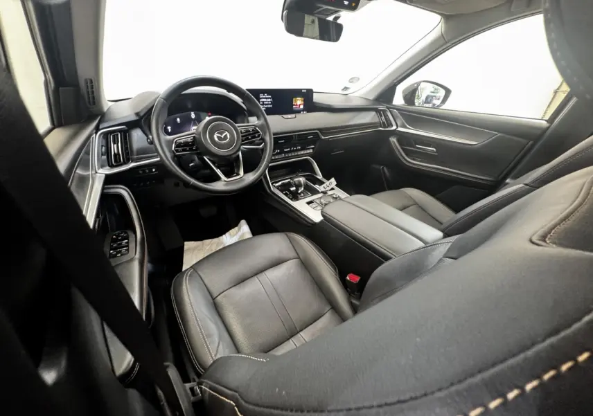Intérieur noir du Mazda CX-60 2024, vue côté conducteur, tableau de bord moderne avec écran tactile central.