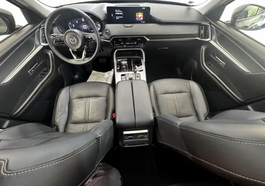 Vue intérieure avant du Mazda CX-60 noir 2024, avec tableau de bord moderne et écran tactile central.