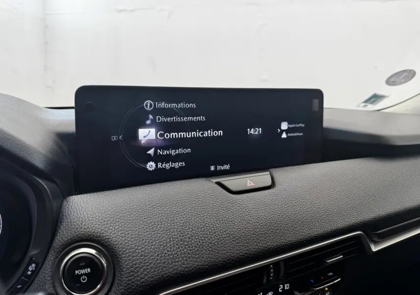 Vue rapprochée de l’écran tactile central du tableau de bord noir du Mazda CX-60 2024 affichant le menu Communication.