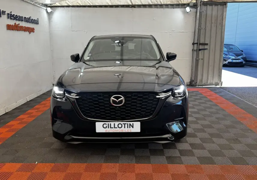 Vue frontale du Mazda CX-60 noir 2024 avec calandre imposante et phares LED allumés dans un showroom.