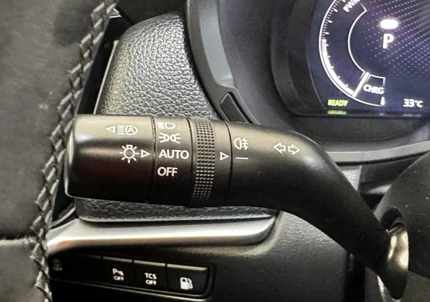 Gros plan sur la commande des phares et clignotants du tableau de bord noir du Mazda CX-60 hybride 2024.