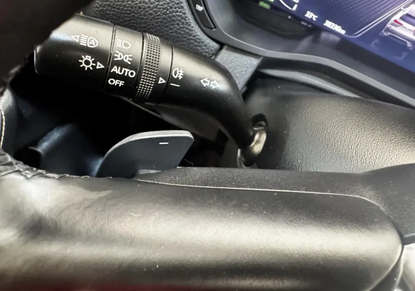 Gros plan sur la manette de commande des phares et clignotants du tableau de bord noir du Mazda CX-60 2024.