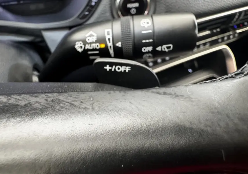 Gros plan sur le volant noir et la commande de régulateur de vitesse +/OFF du Mazda CX-60 2024 hybride rechargeable.