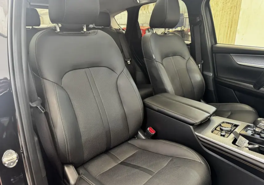 Vue intérieure côté conducteur du Mazda CX-60 noir 2024, sièges cuir noirs et console centrale avec molette de sélection.
