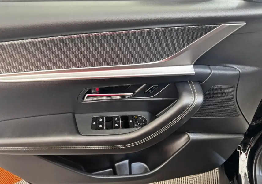Vue rapprochée de la porte avant gauche noire du Mazda CX-60 2024, avec commandes de vitres et insert argenté.