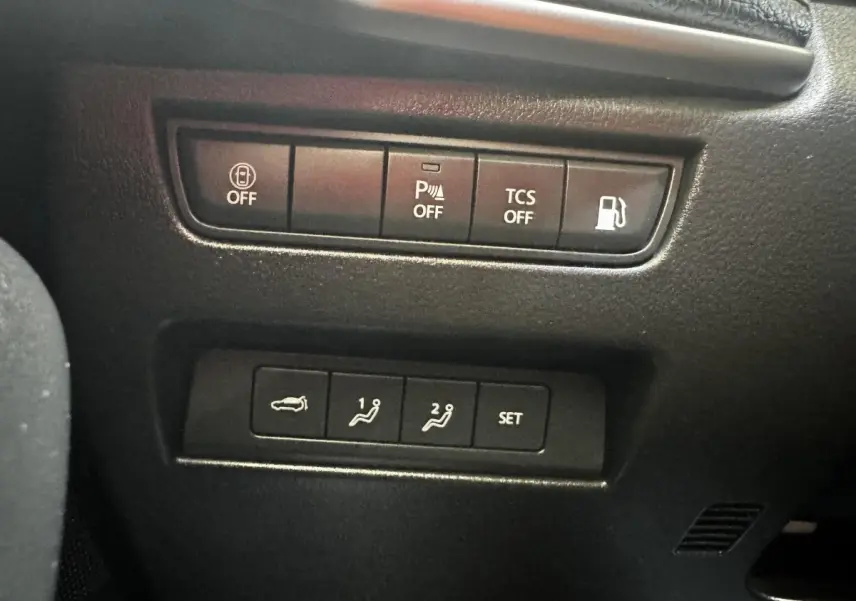 Gros plan sur les boutons de commande intérieurs du Mazda CX-60 noir, avec fonctions parking, traction et ouverture coffre.
