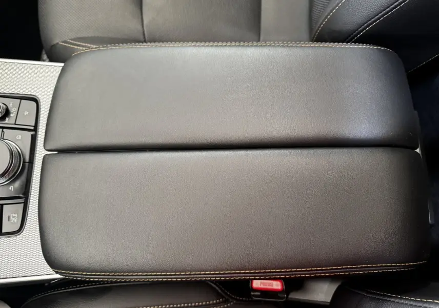 Vue rapprochée de l'accoudoir central en cuir noir avec surpiqûres beiges du Mazda CX-60 2024.