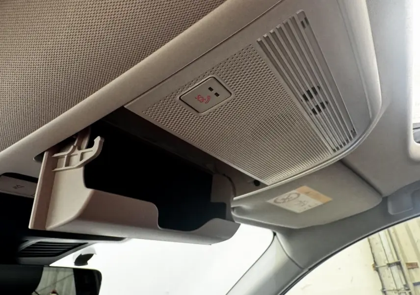 Détail intérieur du plafond de la Mazda CX-60 noir, montrant le rangement lunettes ouvert et le bouton SOS.