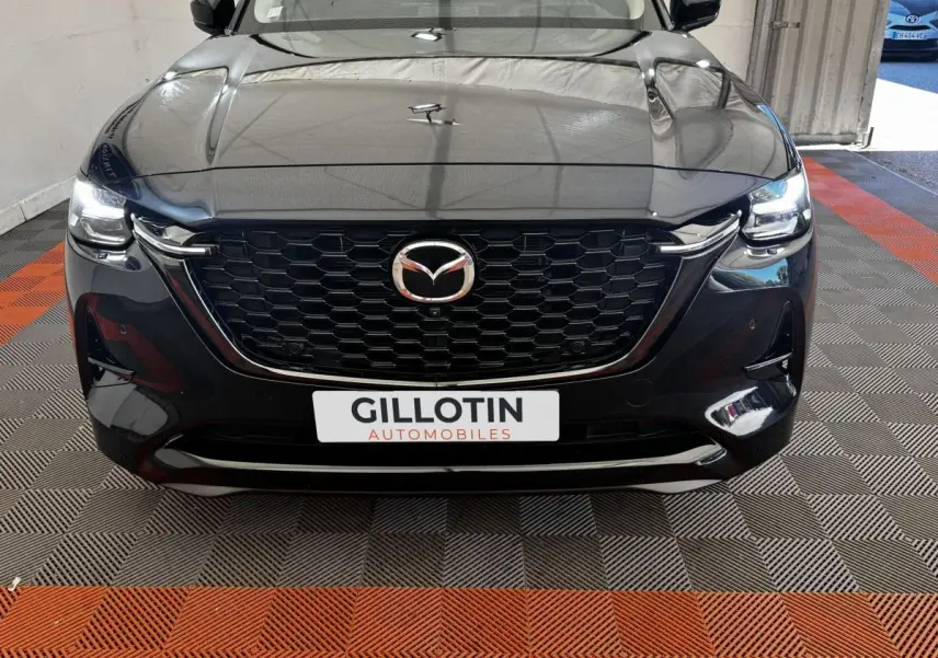 Vue frontale d'un Mazda CX-60 noir 2024 avec calandre hexagonale et phares LED allumés.
