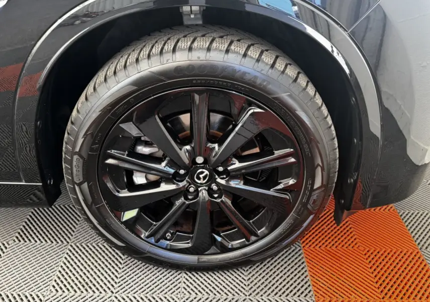 Gros plan sur la roue avant droite noire brillante du Mazda CX-60 2024 avec jante alliage et pneu Goodyear.