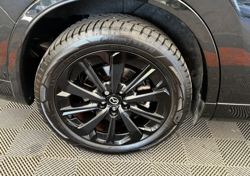 Gros plan sur la roue avant droite noire brillante du Mazda CX-60 2.5 e-Sky PHEV Homura avec jante en alliage noir.