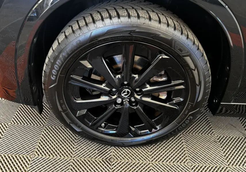 Gros plan sur la roue avant gauche noire avec jante alliage brillante du Mazda CX-60 2.5 e-Sky PHEV Homura 2024.