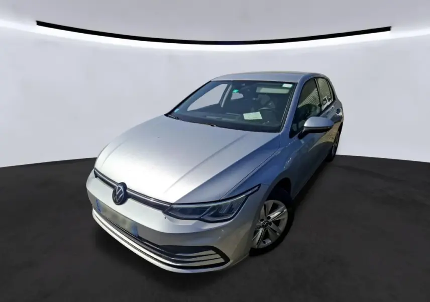 Volkswagen Golf gris clair vue 3/4 avant droit, mettant en valeur ses phares LED et la calandre épurée.