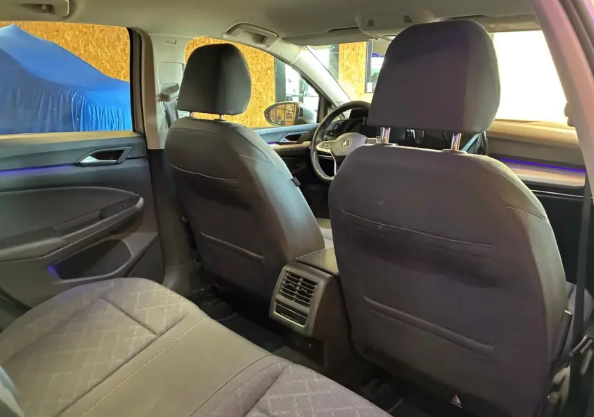 Vue intérieure arrière de la Volkswagen Golf gris clair 2023, montrant les sièges avant et arrière avec éclairage d'ambiance bleu.