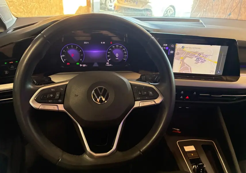Vue intérieure centrée sur le volant Volkswagen d'une Golf 2023, avec tableau de bord numérique et écran tactile de navigation.