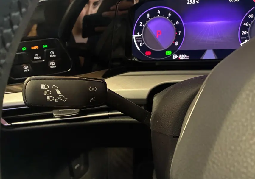 Vue rapprochée du combiné d'instruments et du commodo gauche d'une Volkswagen Golf gris clair 2023, affichage digital violet.
