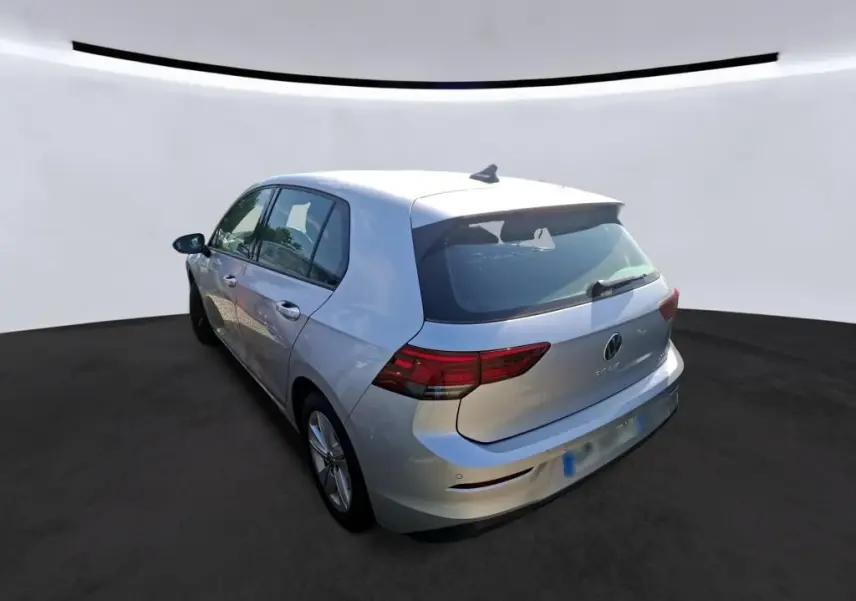 Volkswagen Golf gris clair vue 3/4 arrière droit, mettant en valeur les feux arrière et la silhouette compacte.
