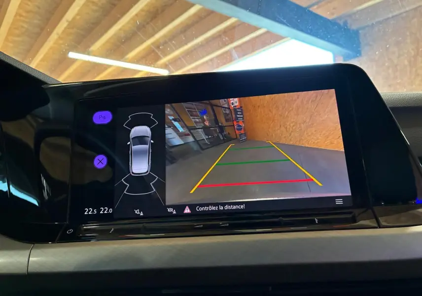 Écran central de la Volkswagen Golf 2023 gris clair montrant la caméra de recul avec guidage coloré et alertes.