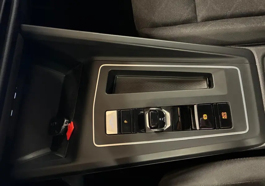 Vue rapprochée de la console centrale gris foncé de la Volkswagen Golf 2023 avec sélecteur de vitesse électronique et frein à main automatique.