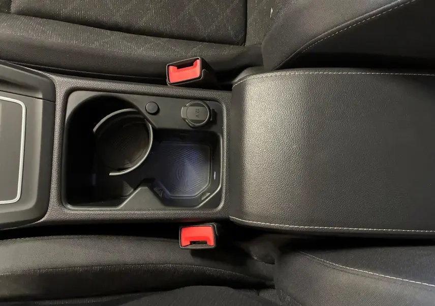 Vue plongeante sur la console centrale noire de la Volkswagen Golf 1.0 eTSI 110 DSG7 Life Plus 2023 avec porte-gobelet et prise 12V.