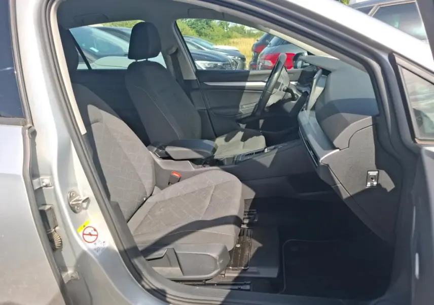 Vue intérieure côté conducteur de la Volkswagen Golf 1.0 eTSI 110 DSG7 Life Plus 2023 gris clair, sièges tissu gris et tableau de bord moderne.