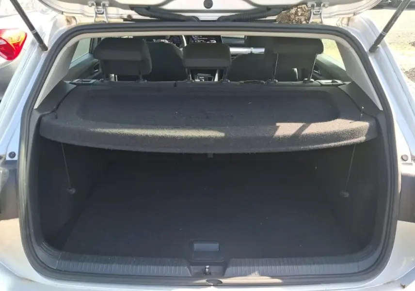 Coffre ouvert vu de l'arrière d'une Volkswagen Golf gris clair 2023, avec cache-bagages en place.