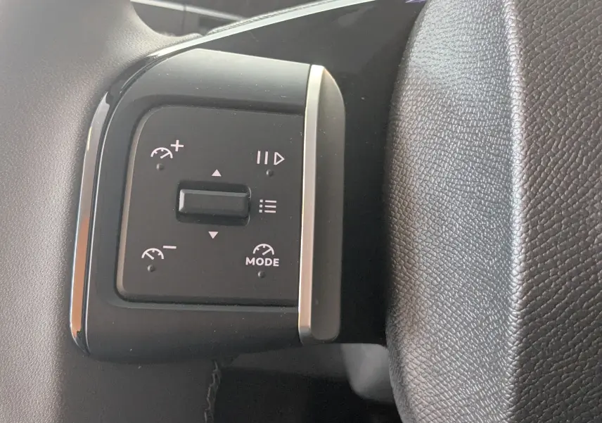 Gros plan sur les commandes noires du régulateur de vitesse dans l'habitacle gris foncé du Citroën E-C3 113 MAX 2025.