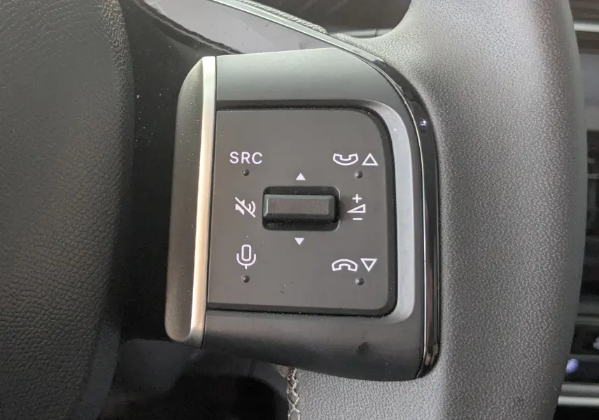 Gros plan sur les commandes noires du volant de la Citroën E-C3 113 MAX 2025, avec boutons de volume et appels.