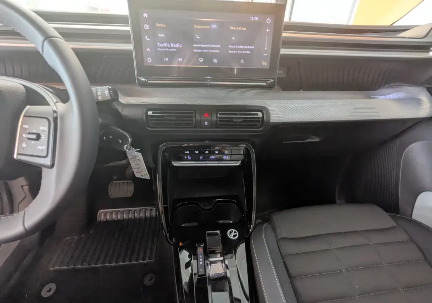 Vue intérieure avant de la Citroën E-C3 113 MAX 2025, tableau de bord noir avec écran tactile et console centrale brillante.