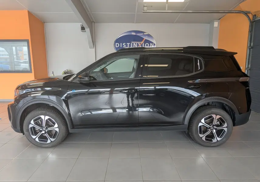Vue de profil côté gauche d'une Citroën C3 E-C3 113 MAX noire, avec jantes alliage 17 pouces bicolores en intérieur showroom.