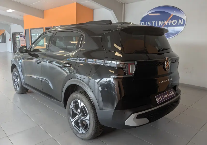 Vue 3/4 arrière droite d'un Citroën C3 Aircross noir brillant avec jantes alliage bicolores en showroom.