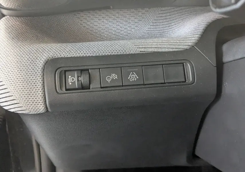 Détail des commandes de réglage d’éclairage et d’aide à la conduite sur la planche de bord grise et noire d’une Citroën C3 E-C3 113 MAX.
