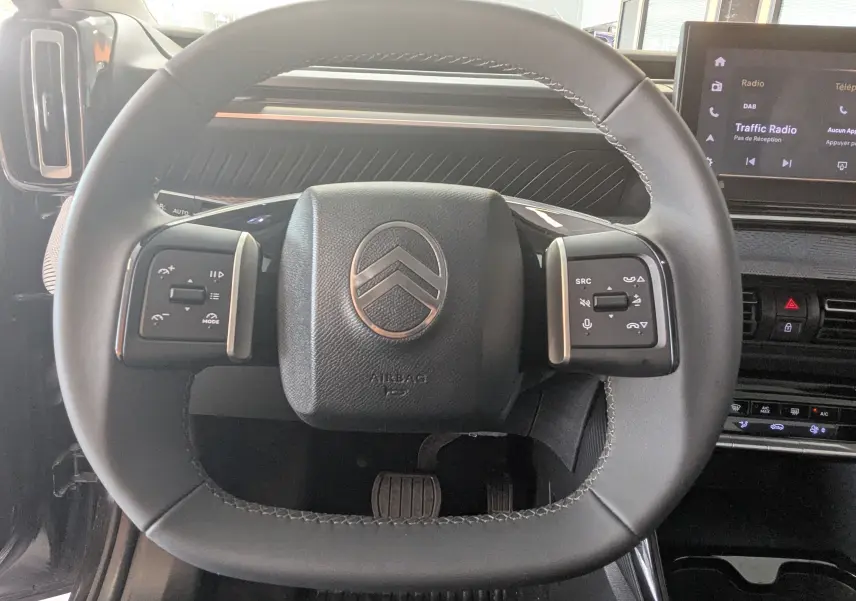 Vue rapprochée du volant noir de la Citroën E-C3 113 MAX 2025 avec commandes intégrées et tableau de bord moderne.