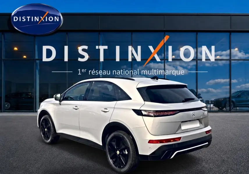 DS7 1.5 BlueHDi 130 Crystal Pearl vue 3/4 arrière droit avec jantes noires et vitres surteintées devant un showroom Distinxion.