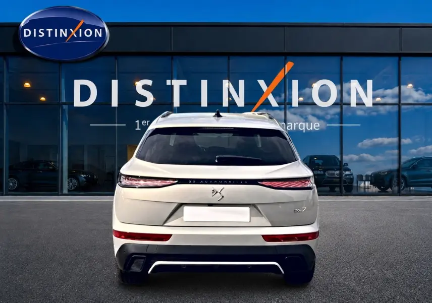 Vue arrière d'un DS7 Crystal pearl 2026 avec feux LED fins et double sortie d'échappement, devant une vitrine Distinxion.