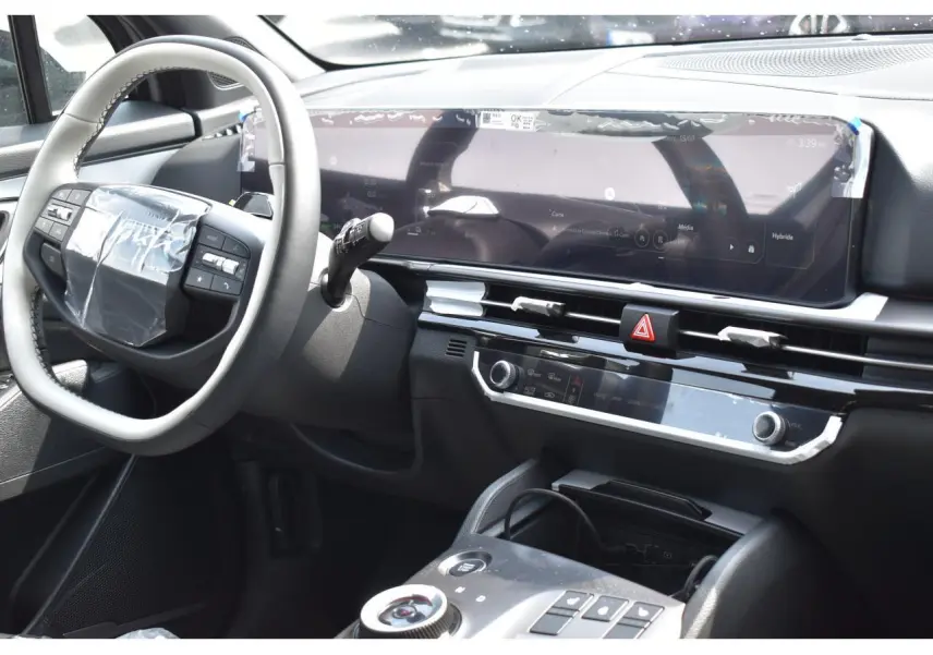 Vue intérieure côté conducteur du tableau de bord du Kia Sportage hybride gris avec écran digital large et volant multifonction.