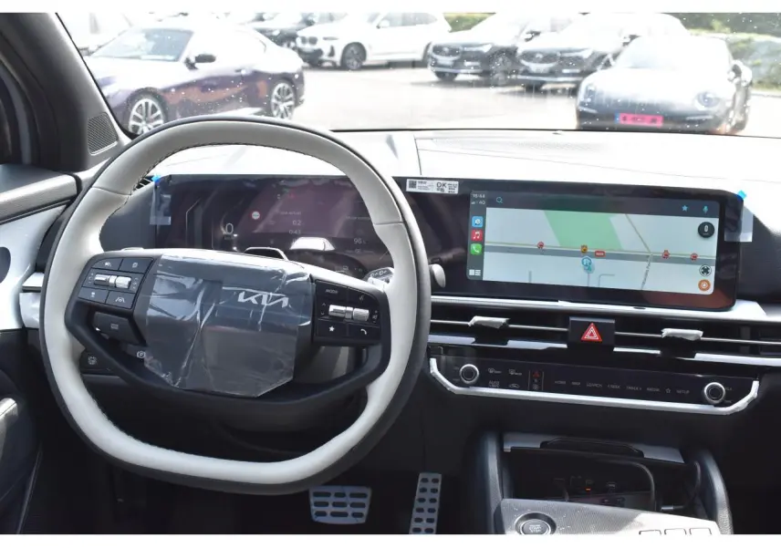 Intérieur du Kia Sportage hybride 2026 vu de face, tableau de bord avec écran tactile et volant bi-ton gris et noir.