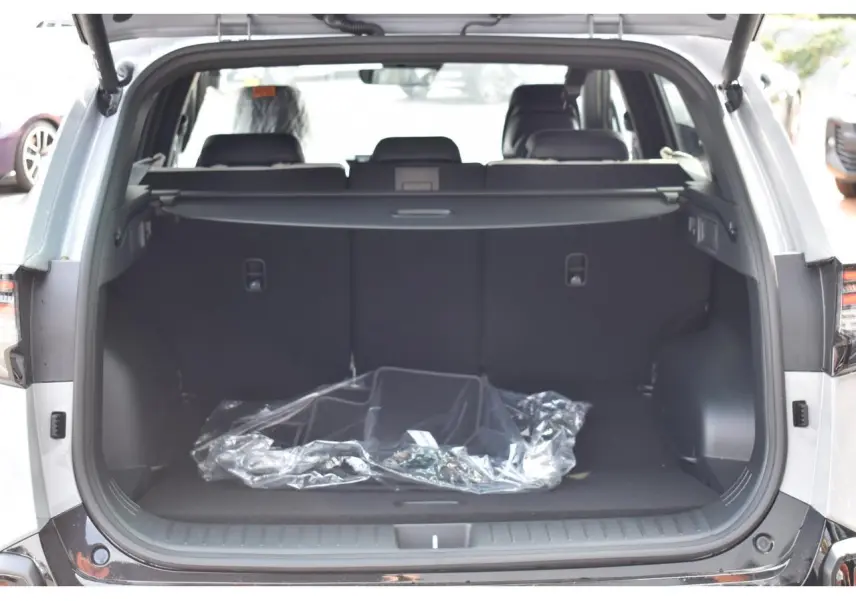 Coffre ouvert vu de l'arrière d'un KIA Sportage gris 2026, montrant l'espace de chargement vide avec cache-bagages.