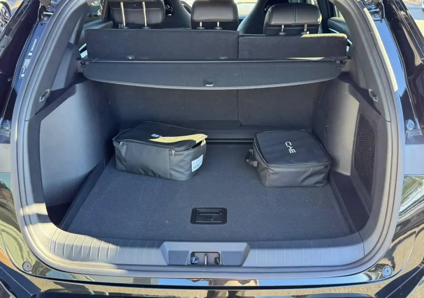 Coffre ouvert du BYD SEAL U 2026 Obsidian Black métallisé, vue arrière avec cache-bagages et deux sacs noirs.