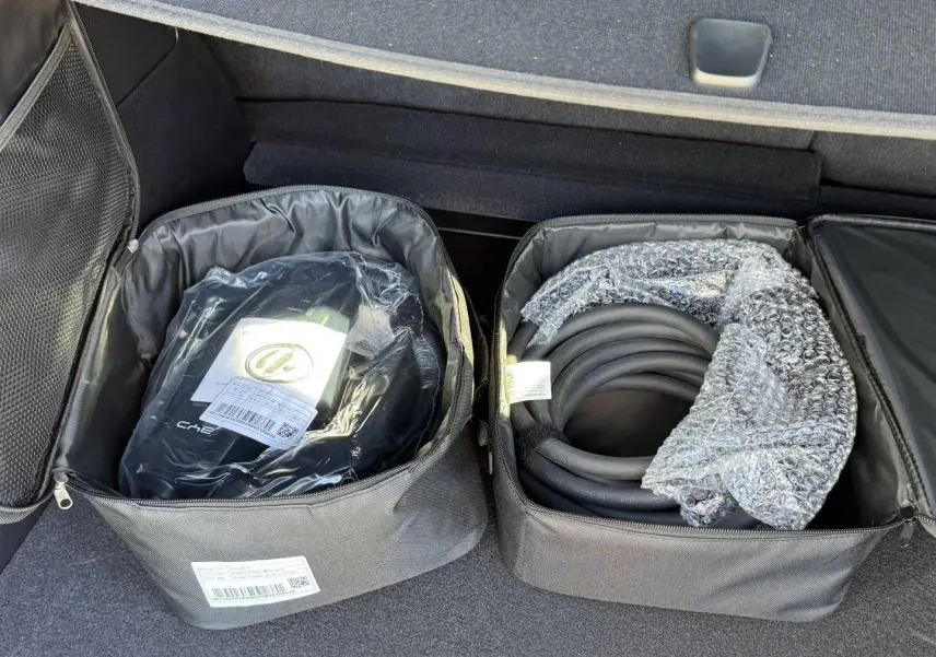 Coffre ouvert d'un BYD SEAL U 1.5 DM-i 324ch Design AWD 2026, montrant les câbles de recharge rangés dans des sacs noirs.
