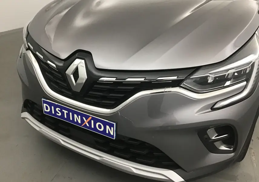 Vue avant rapprochée du Renault Captur gris Cassiopée avec calandre noire et logo chromé bien visible.