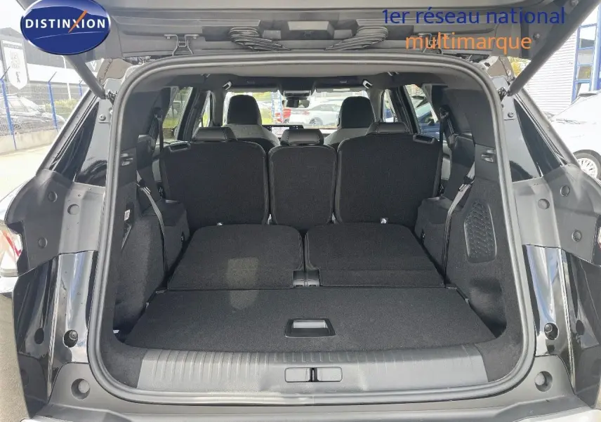 Coffre ouvert du Peugeot 5008 noir perle métal, montrant les sièges arrière rabattus et l'espace de chargement spacieux.