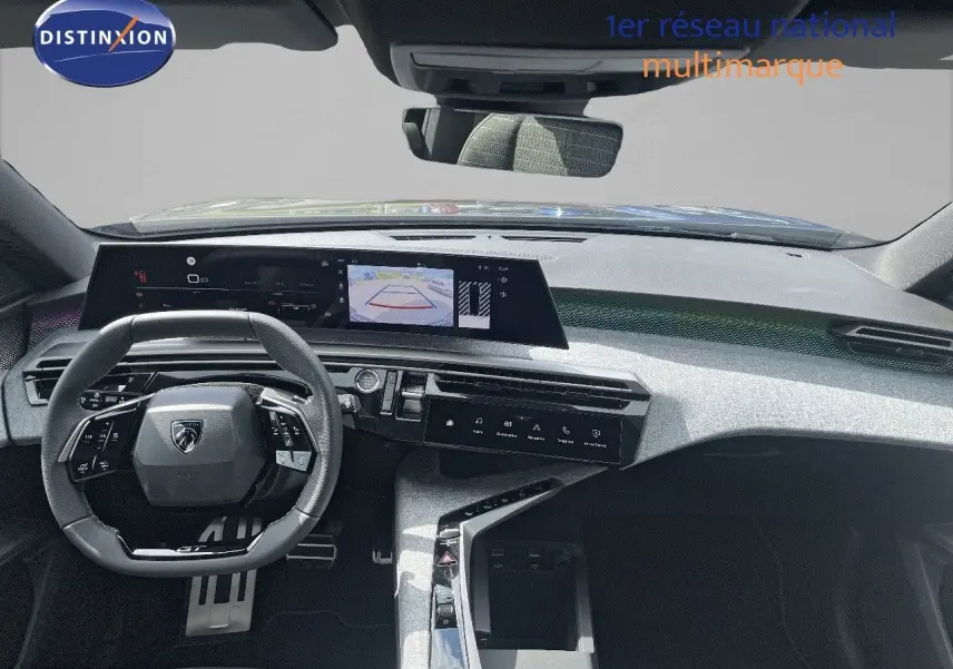 Vue intérieure du tableau de bord et volant noir du Peugeot 5008 Hybrid 136ch GT 2025 avec écran central tactile et caméra de recul affichée.